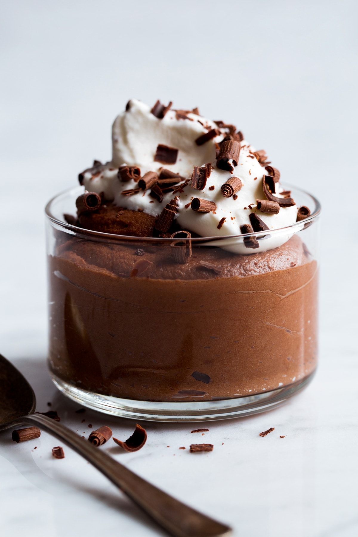 Glass full of chocolate mousse topped with whipped cream and chocolate shavings.