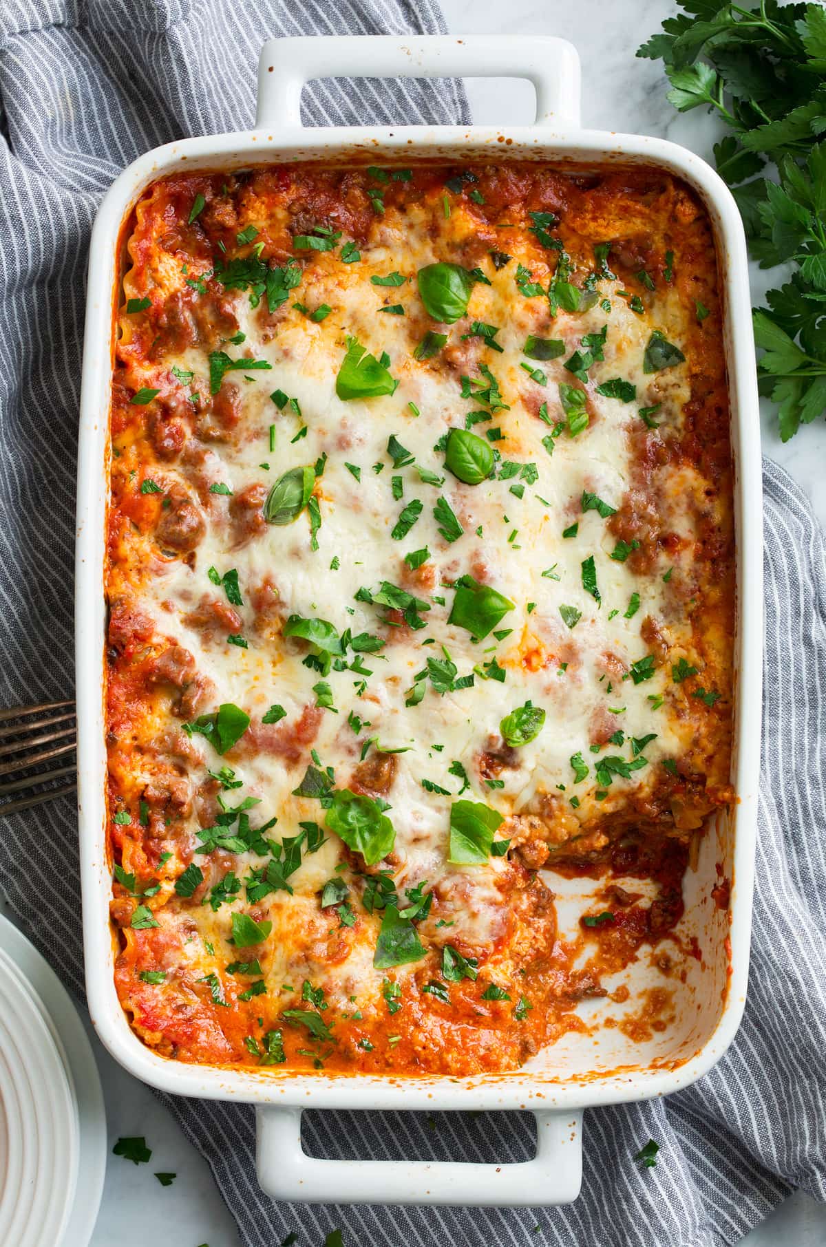 Easy lasagna shown overhead in a white casserole dish with one portion cut out.