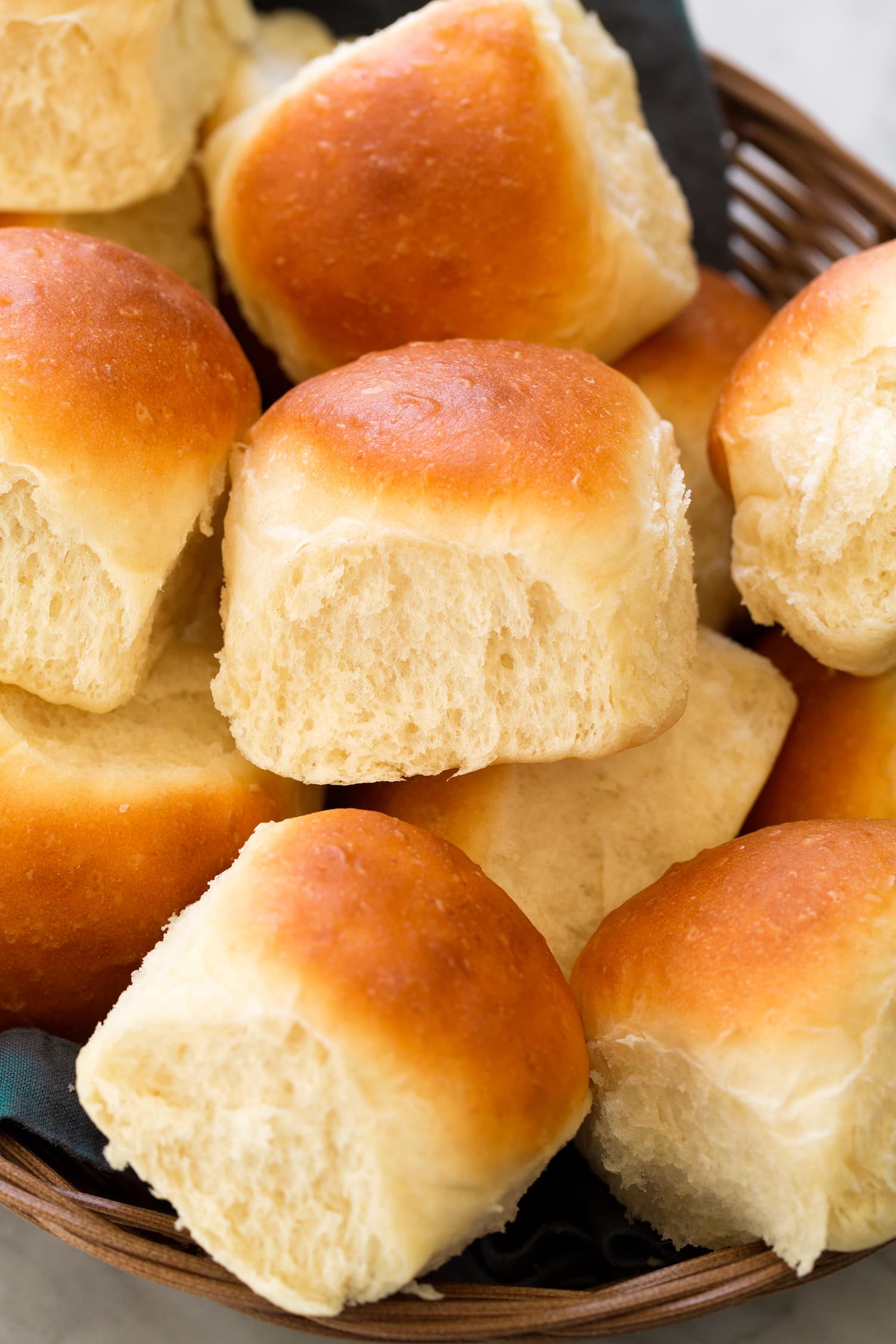 Close up photo of homemade dinner roll showing soft and fluffy texture and golden brown tops.