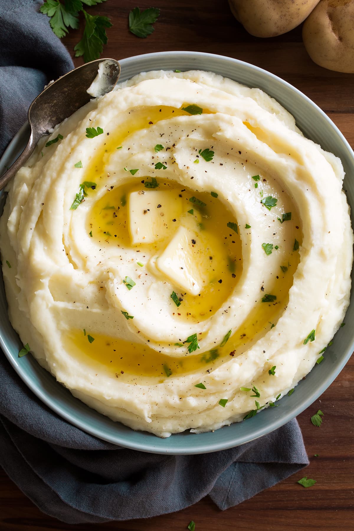 Overhead image of mashed potatoes topped with butter in a grey bowl.