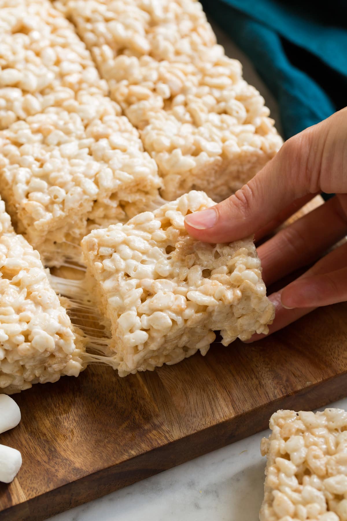 Hand removing rice krispie treat from batch.