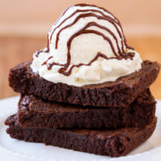 Stack of 3 brownies with ice cream and hot fudge sauce on top.