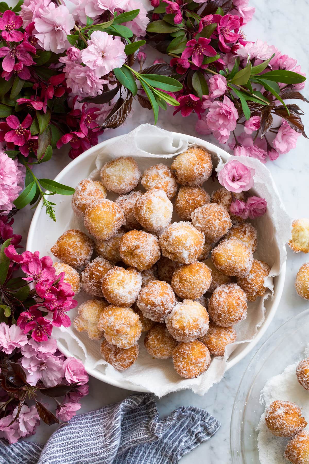 Donut holes in a bowl surrounded by flowers.
