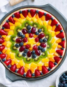 Homemade fruit pizza decorated in a artistic pattern with colorful fresh fruit.