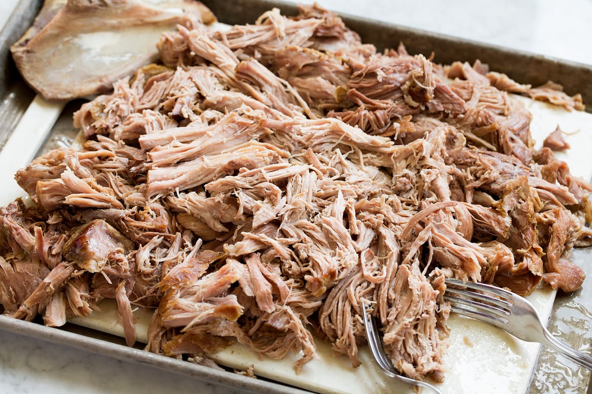 Kalau pork shredded on a cutting board with two forks to the side.