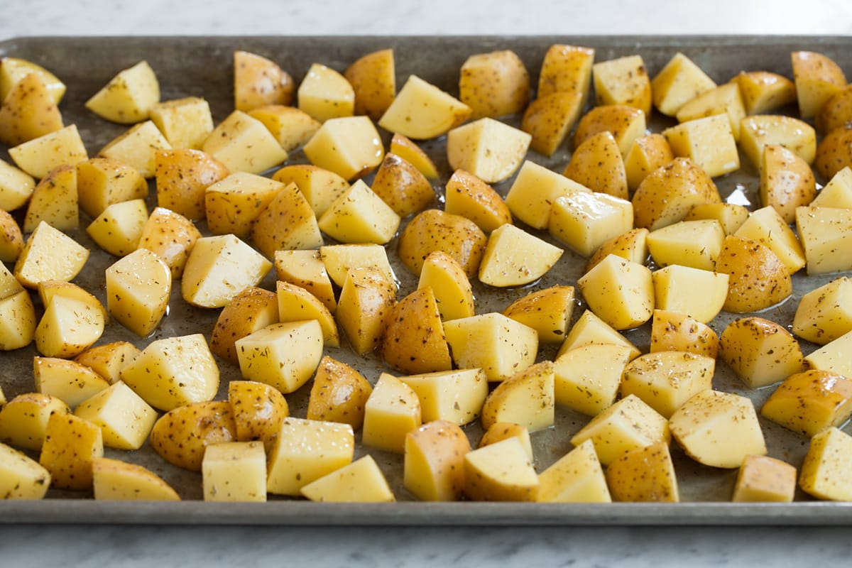 Seasoned yukon gold potatoes spread out on a baking sheet.