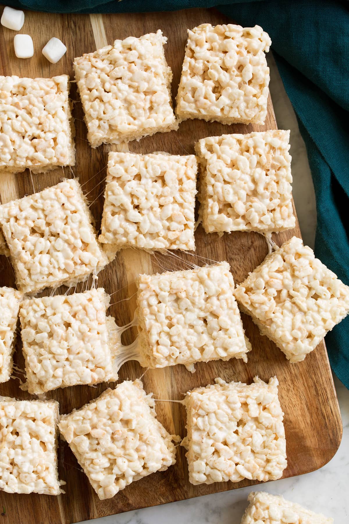 Overhead image of rice krispie treat squares on a wooden cutting board.