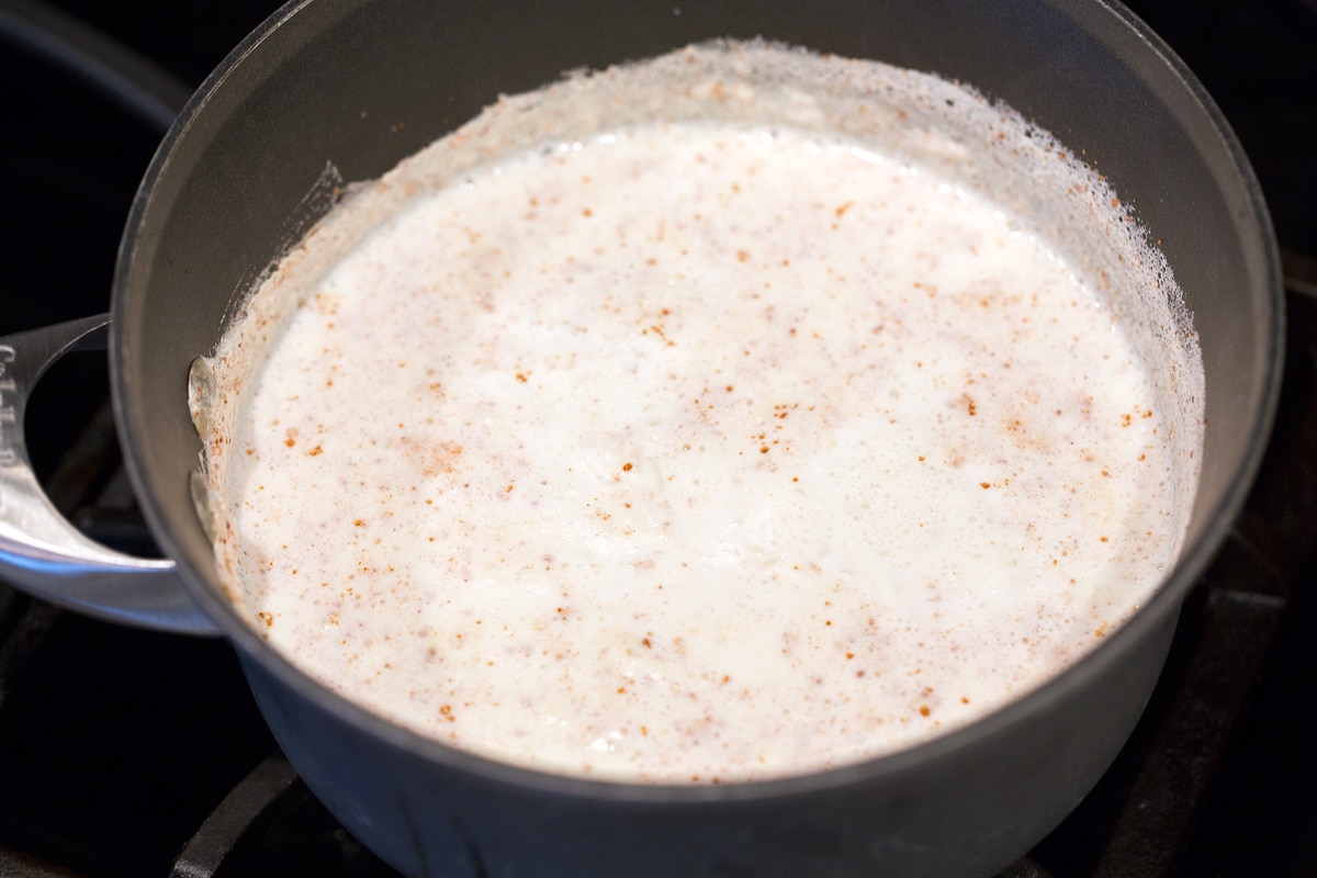 Rice pudding simmering in pan on stovetop.