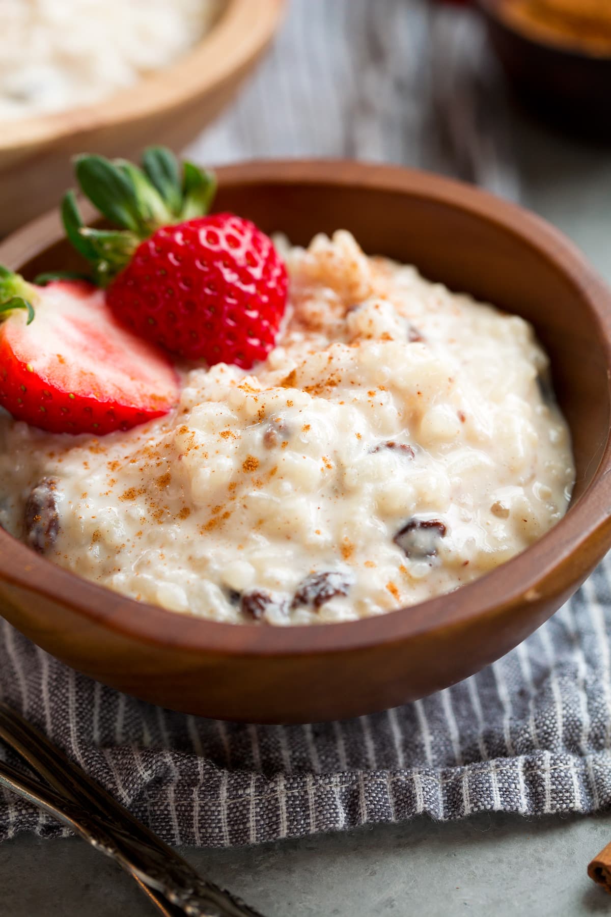 Close up image of rice pudding in a small bowl, garnished with strawberries and cinnamon.