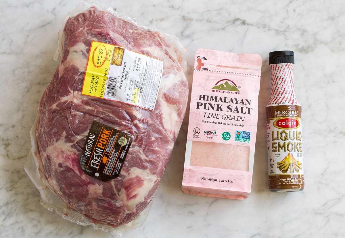 Image of ingredients used for kalua pork. Includes pork shoulder, pink salt, and liquid smoke.