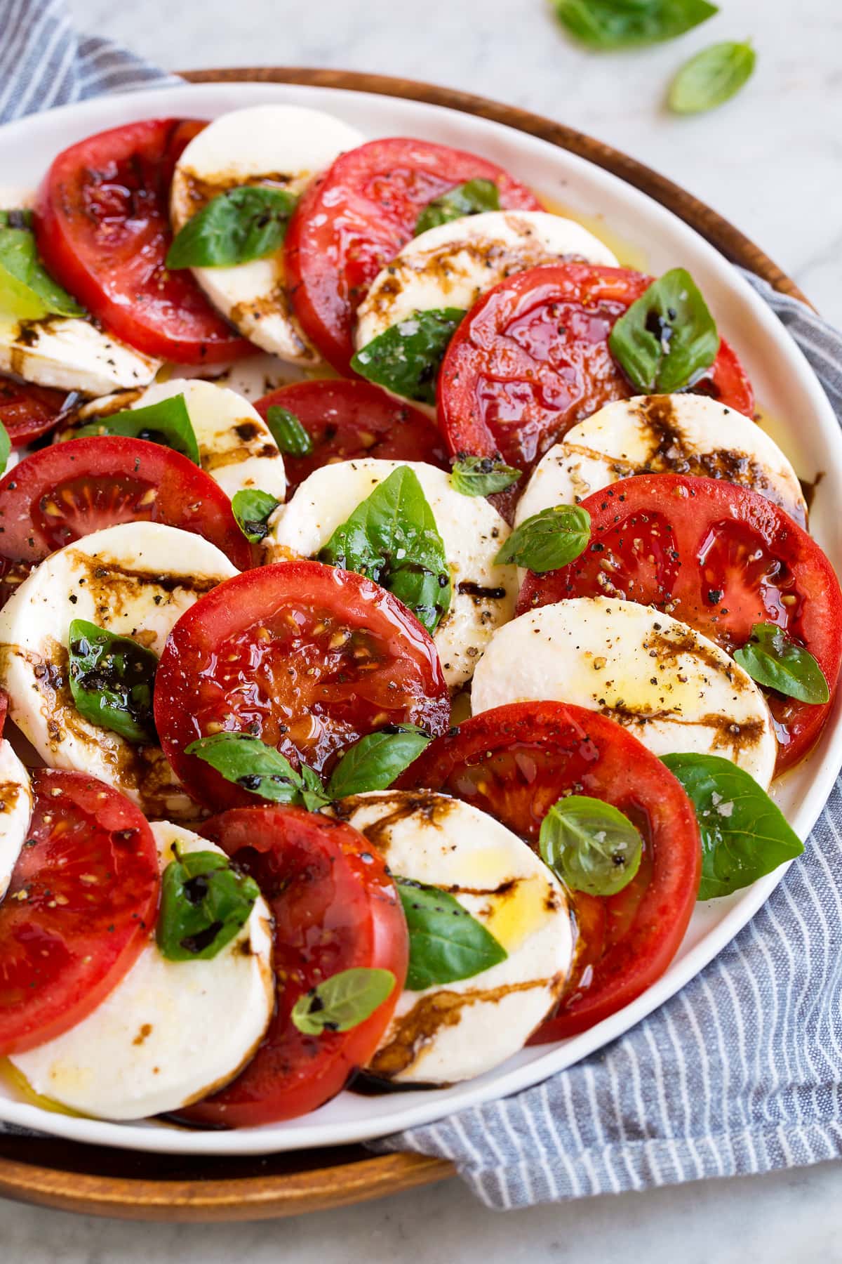 Caprese salad layered in a pretty design shown on a white platter.