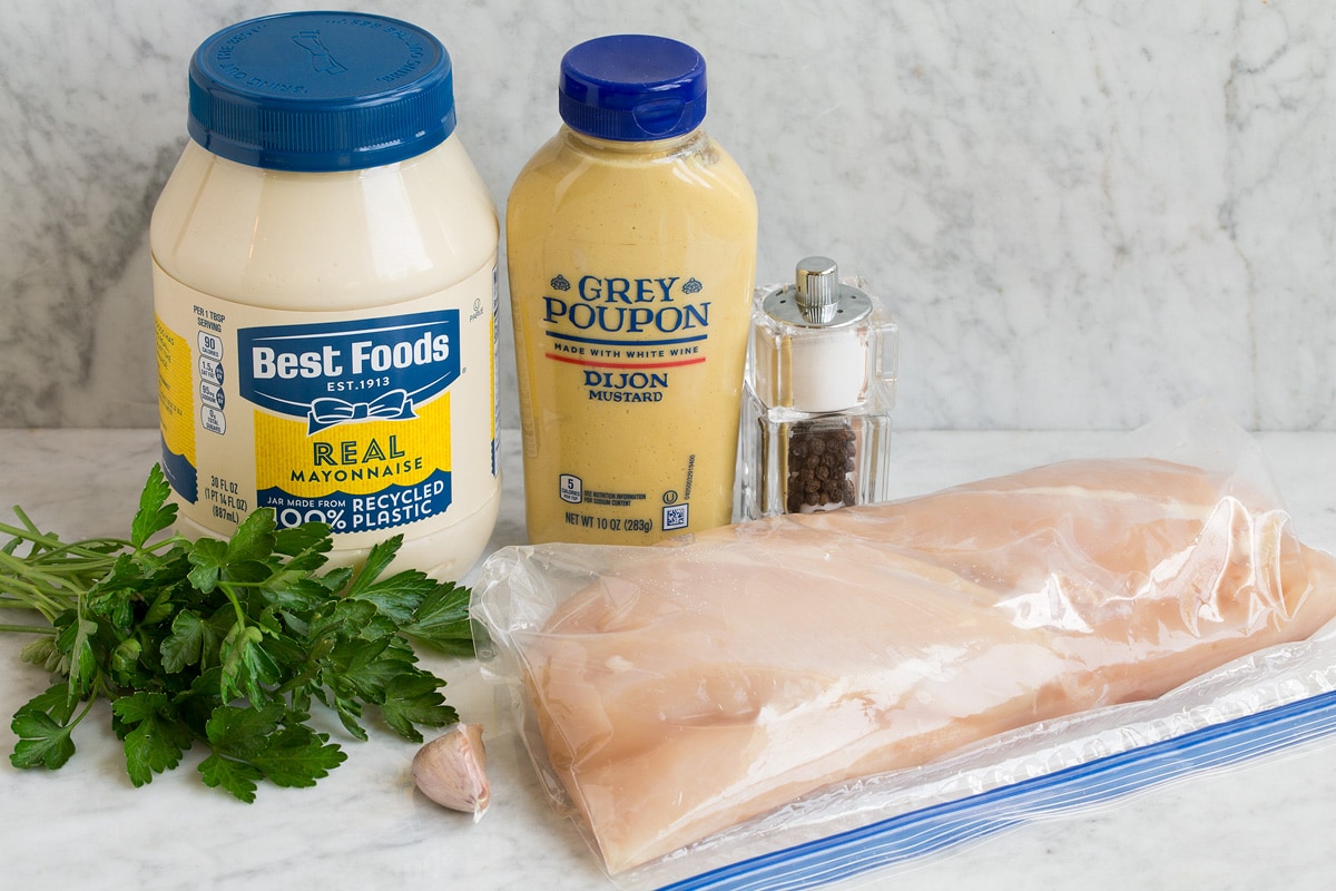 Image of ingredients shown to make dijon chicken. Includes chicken breasts, dijon mustard, mayonnaise, salt and pepper, garlic and optional parsley.