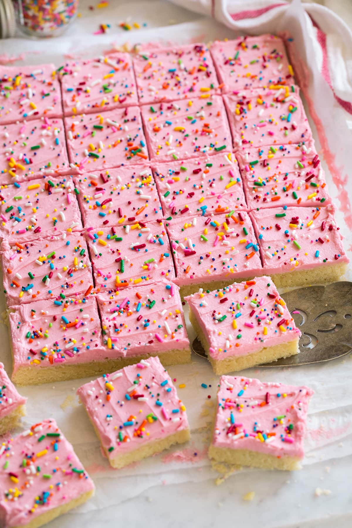 Sugar cookie bars shown cut and laying on parchment paper.
