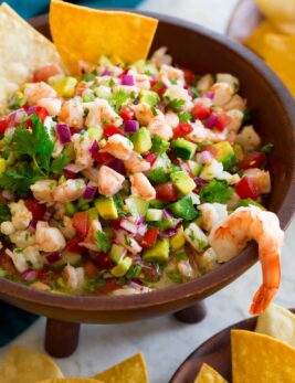 Ceviche in a wooden dip bowl with tortilla chips on the side.