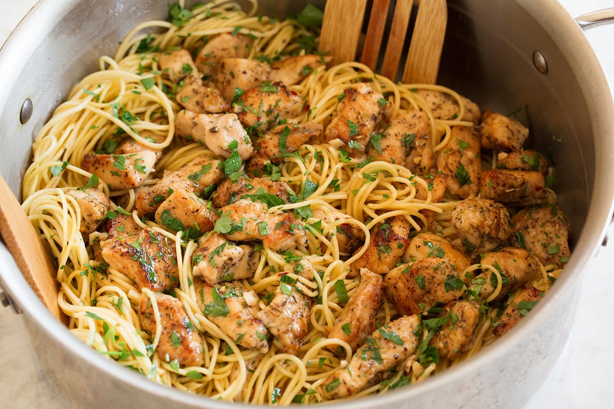 Pasta and chicken scampi pieces being tossed together in a pot.