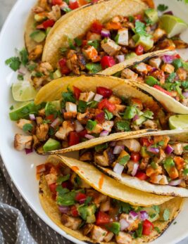 Chicken tacos on a platter shown from a side angle.