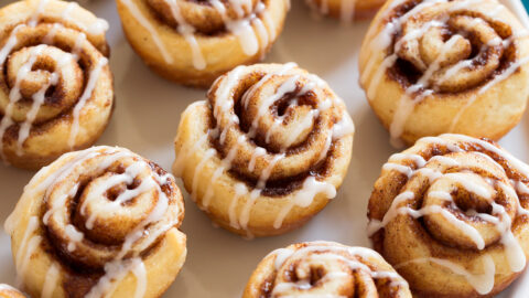Photo of 12 Mini Cinnamon Rolls shown sitting on white platter over a marble surface.
