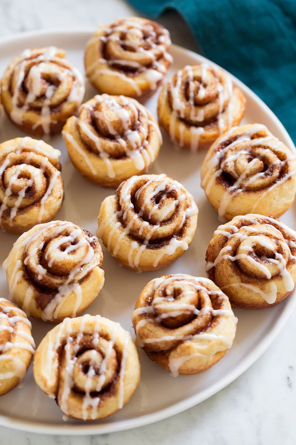 Photo of 12 Mini Cinnamon Rolls shown sitting on white platter over a marble surface.