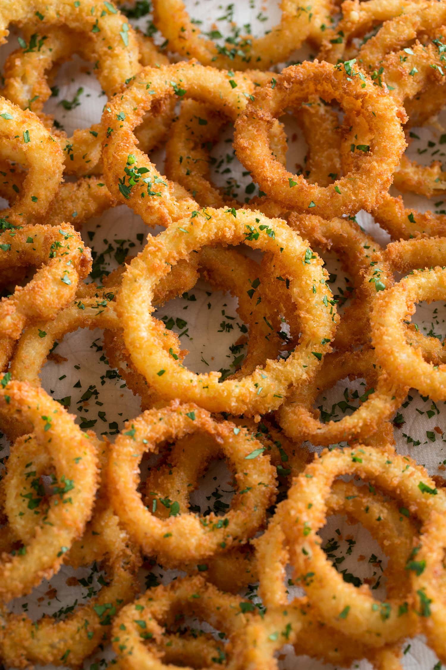 Close up photo of breaded and fried onions layered over each other and garnished with parsley.