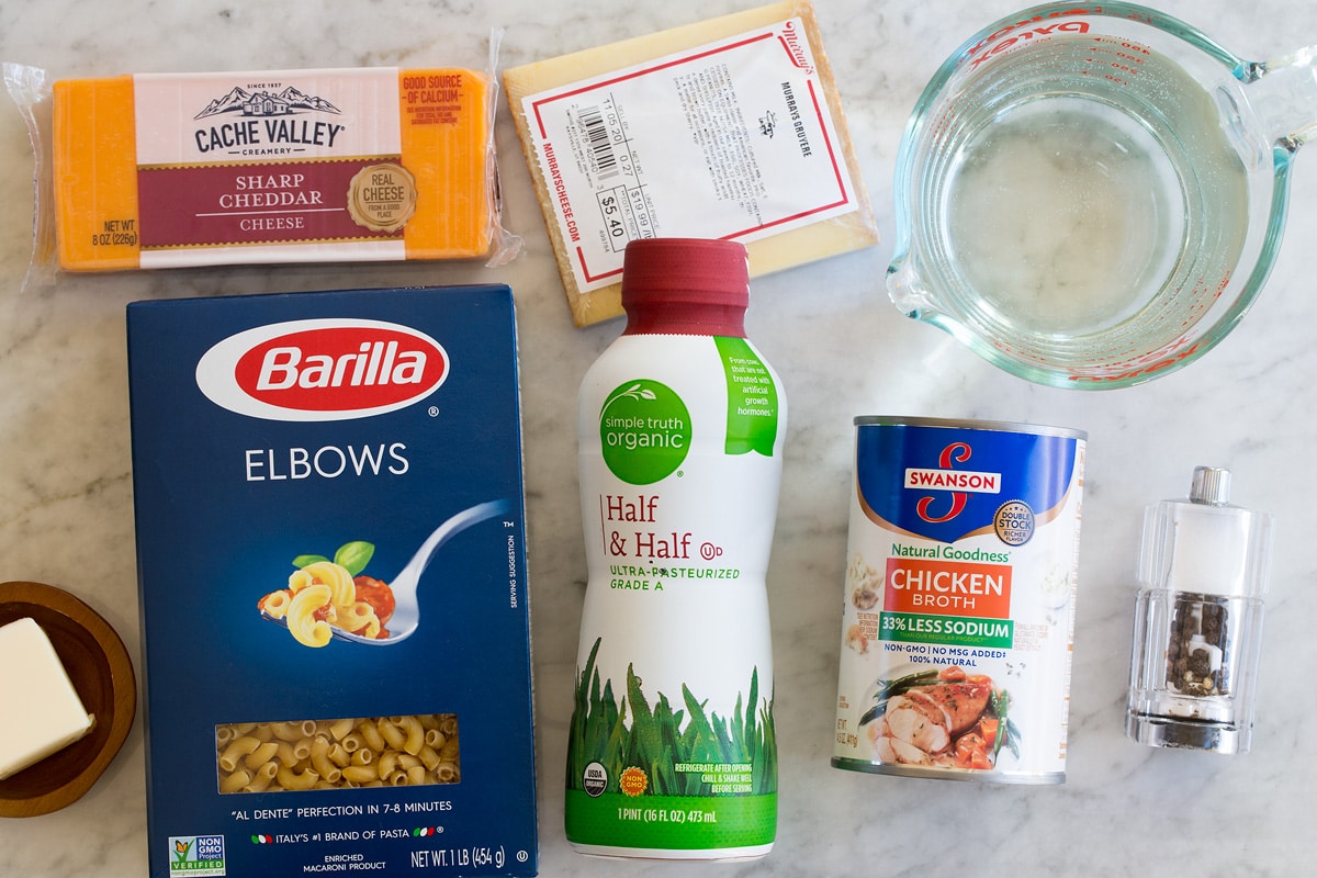 Image of ingredients used to make Instant Pot Mac and Cheese. Includes elbow pasta, cheddar, gruyere, half and half, chicken broth, water, butter, salt and pepper.