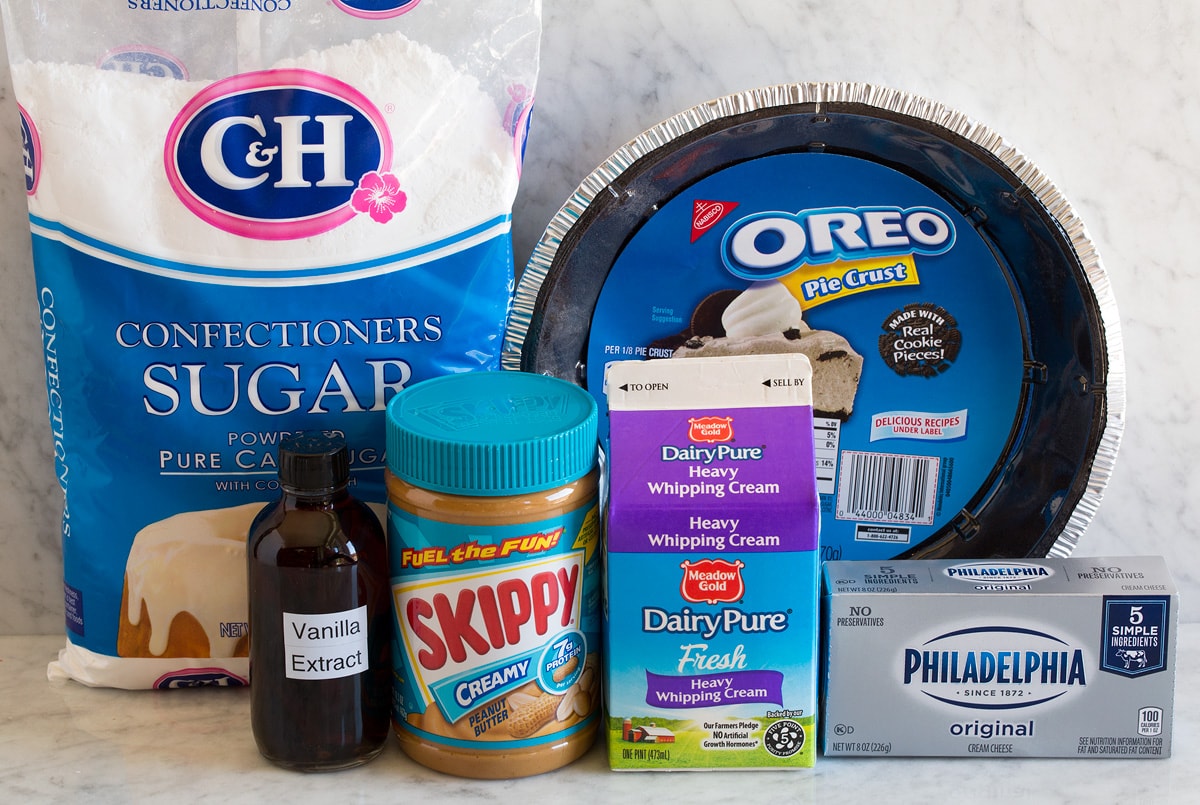Image of ingredients used to make peanut butter pie. Includes Oreo crust, peanut butter, powdered sugar, cream cheese, heavy cream and optional vanilla extract.