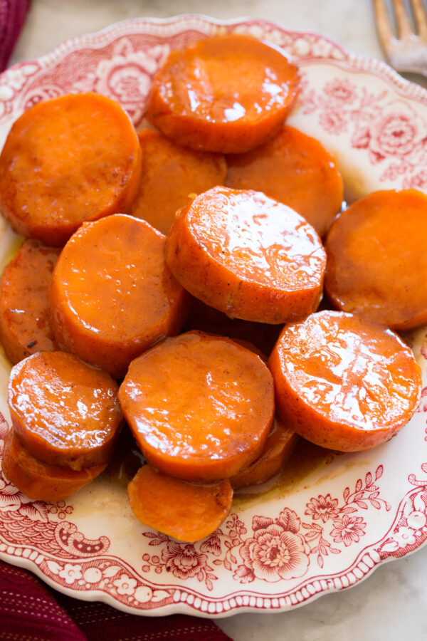 Close up image of candied yams on a red and white decorative side plate.