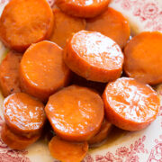 Close up image of candied yams on a red and white decorative side plate.