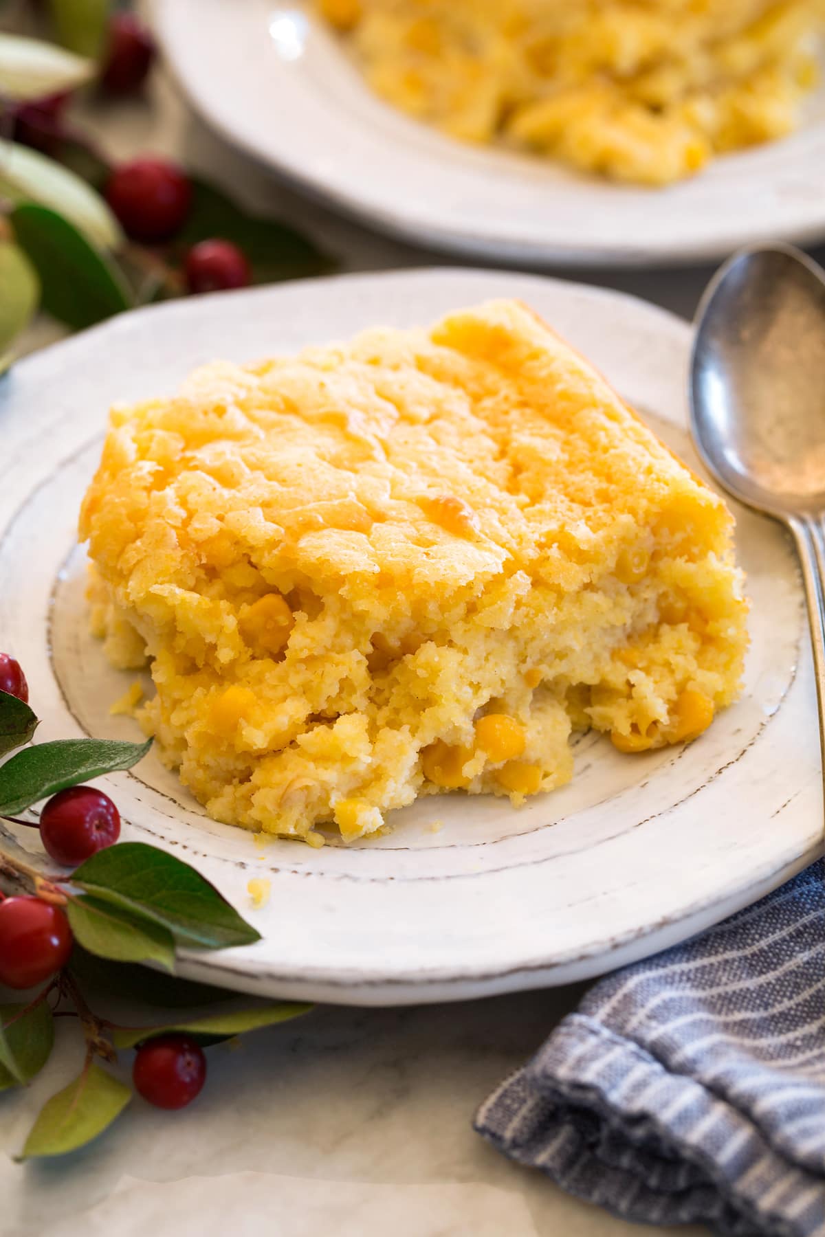 Single serving of corn casserole shown on a white plate with a spoon to the side.