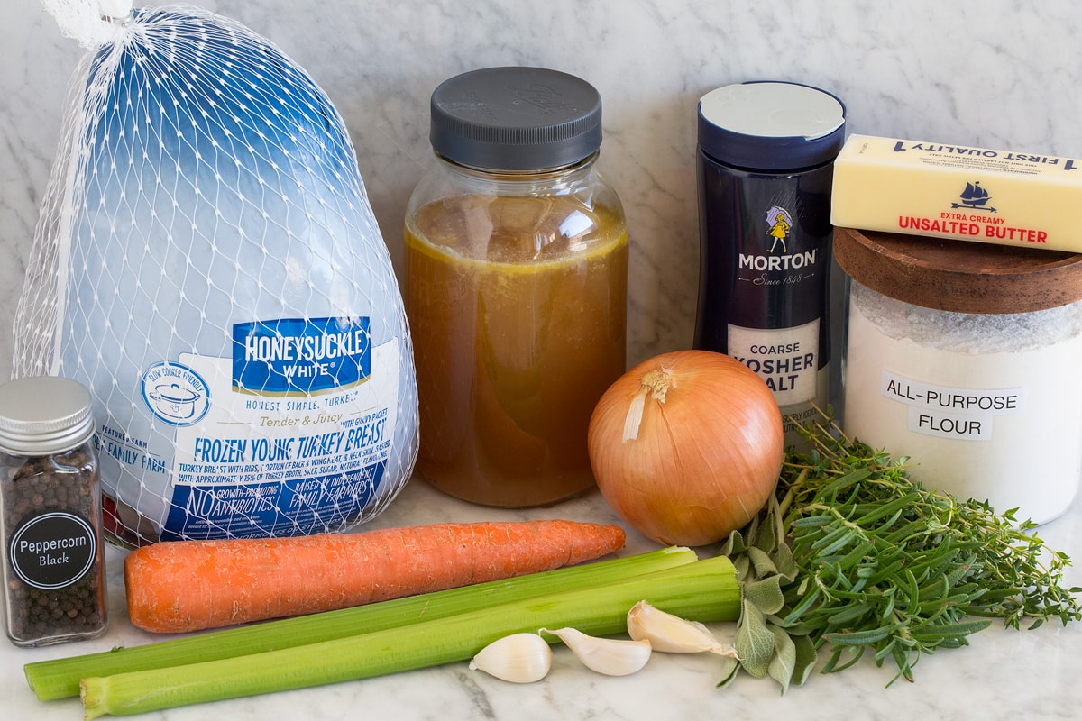 Image of ingredients used to make Roast Turkey Breast and gravy. Shows turkey breast in packaging, broth, salt, pepper, butter, herbs, onions, carrot, celery and garlic.