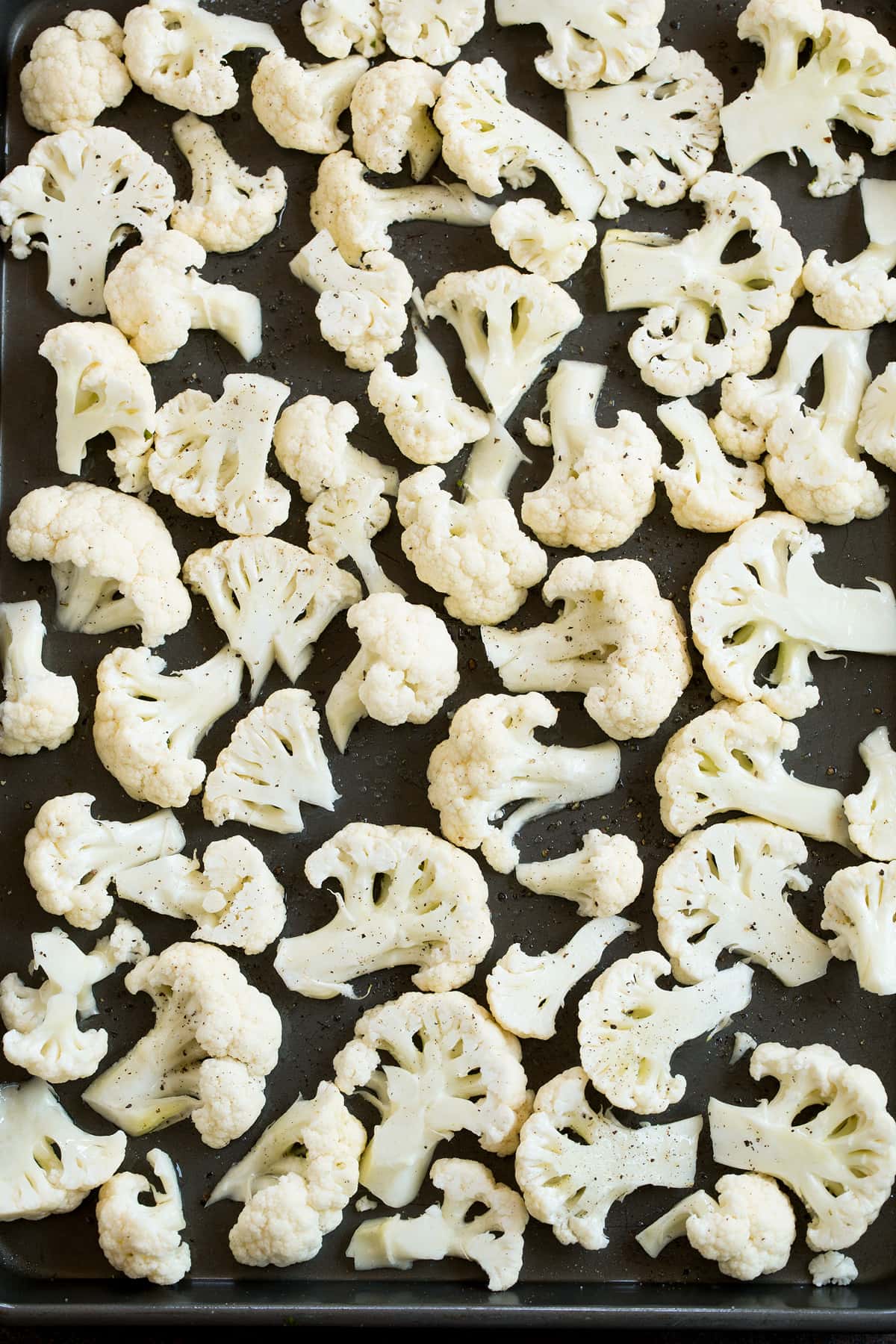 Cauliflower florets on a baking sheet shown before roasting.