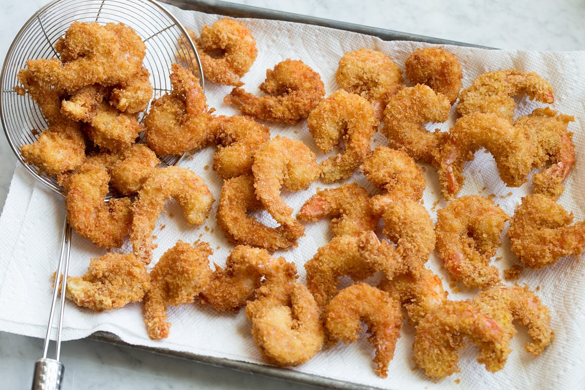 Photo of fried shrimp after frying on a paper towel lined baking sheet.