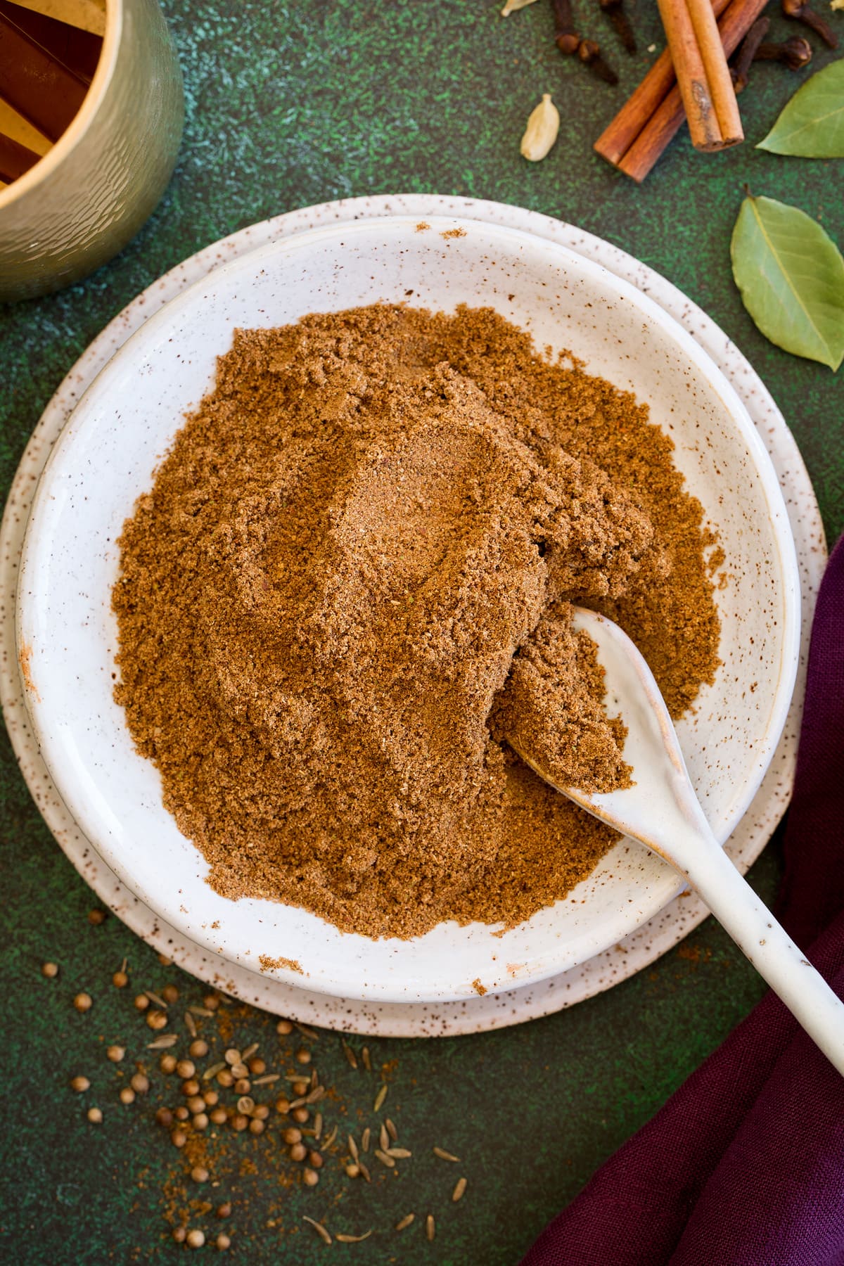 Overhead photo of homemade garam masala spice blend in a bowl with a spoon.