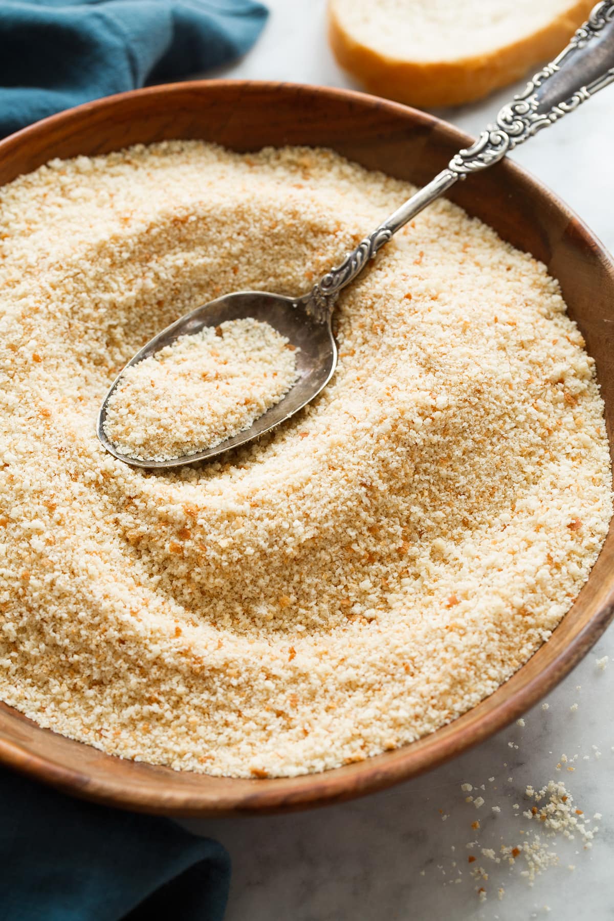 Photo of finished baked bread crumbs in a wooden bowl with a large serving spoon.