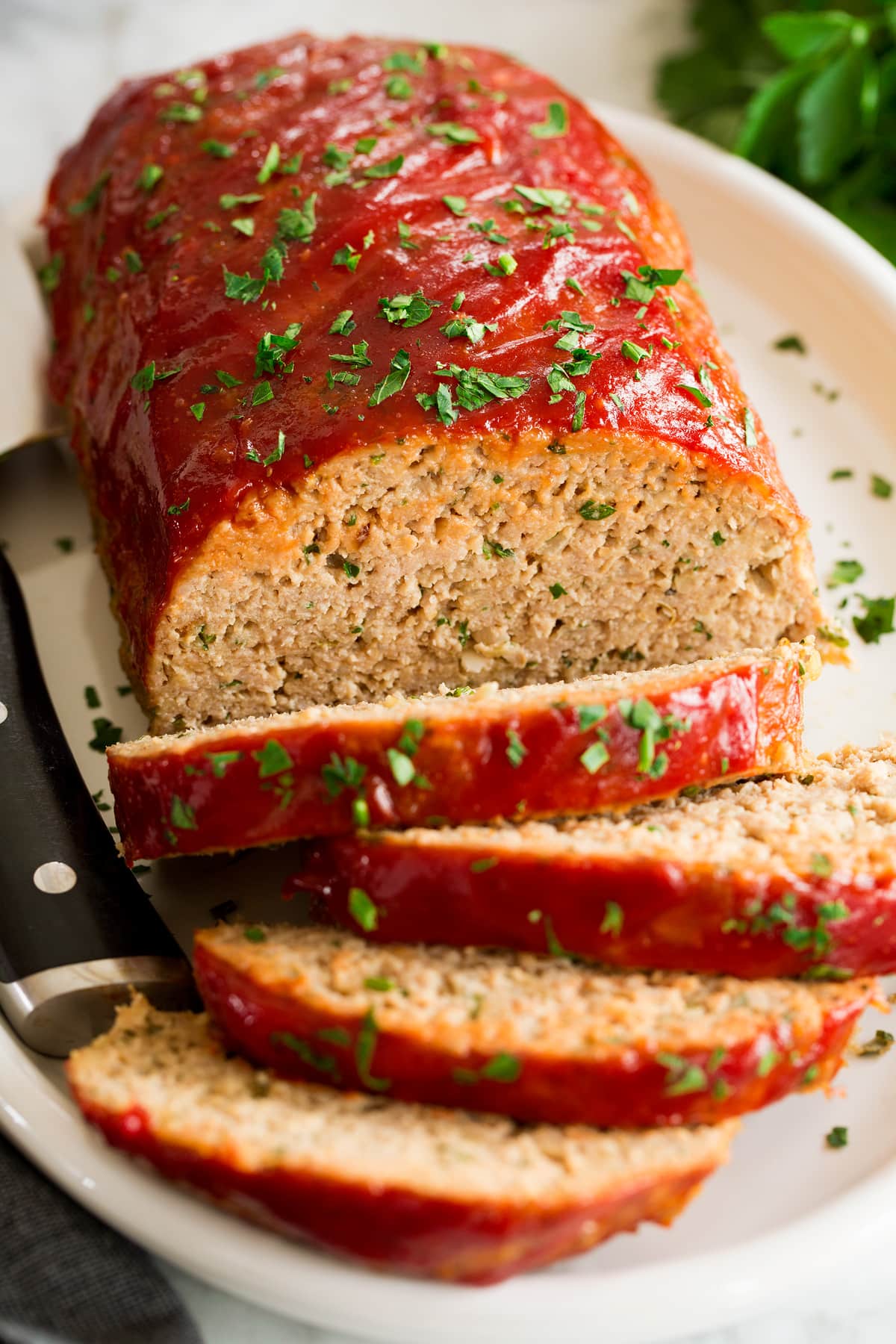 Close up photo of turkey meatloaf with several slices cut. Shown from a side angle.