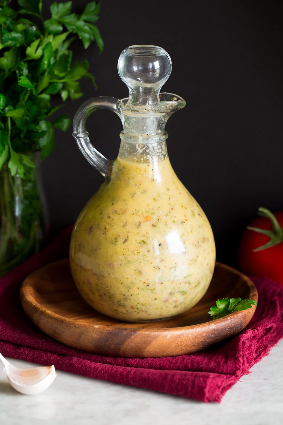 Photo: Italian Dressing in a glass bottle set over a wooden plate and a red cloth.