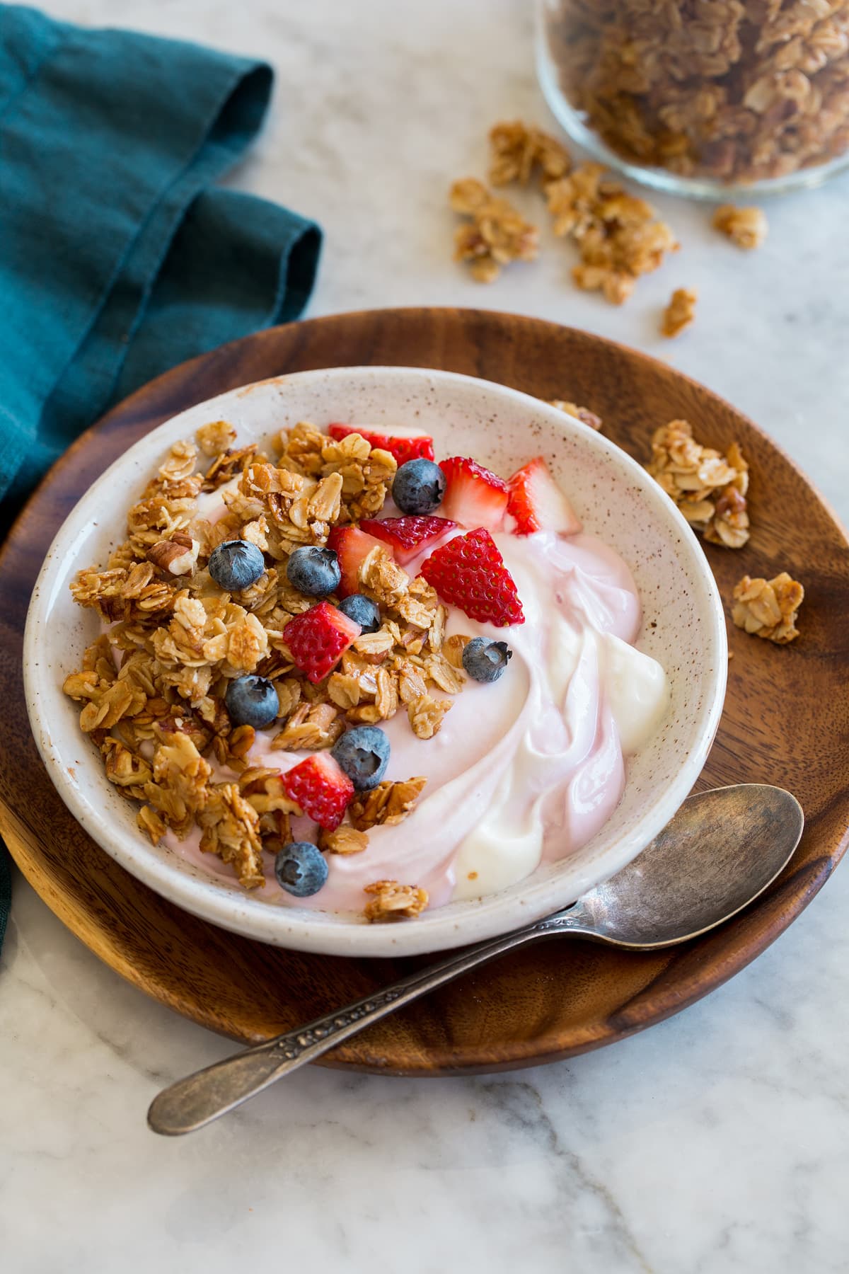 Homemade granola shown in a small serving bowl served over yogurt and fruit.