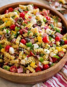 Italian pasta salad shown from a side angle on a large wooden bowl.