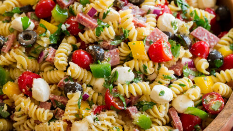 Italian pasta salad shown from a side angle on a large wooden bowl.