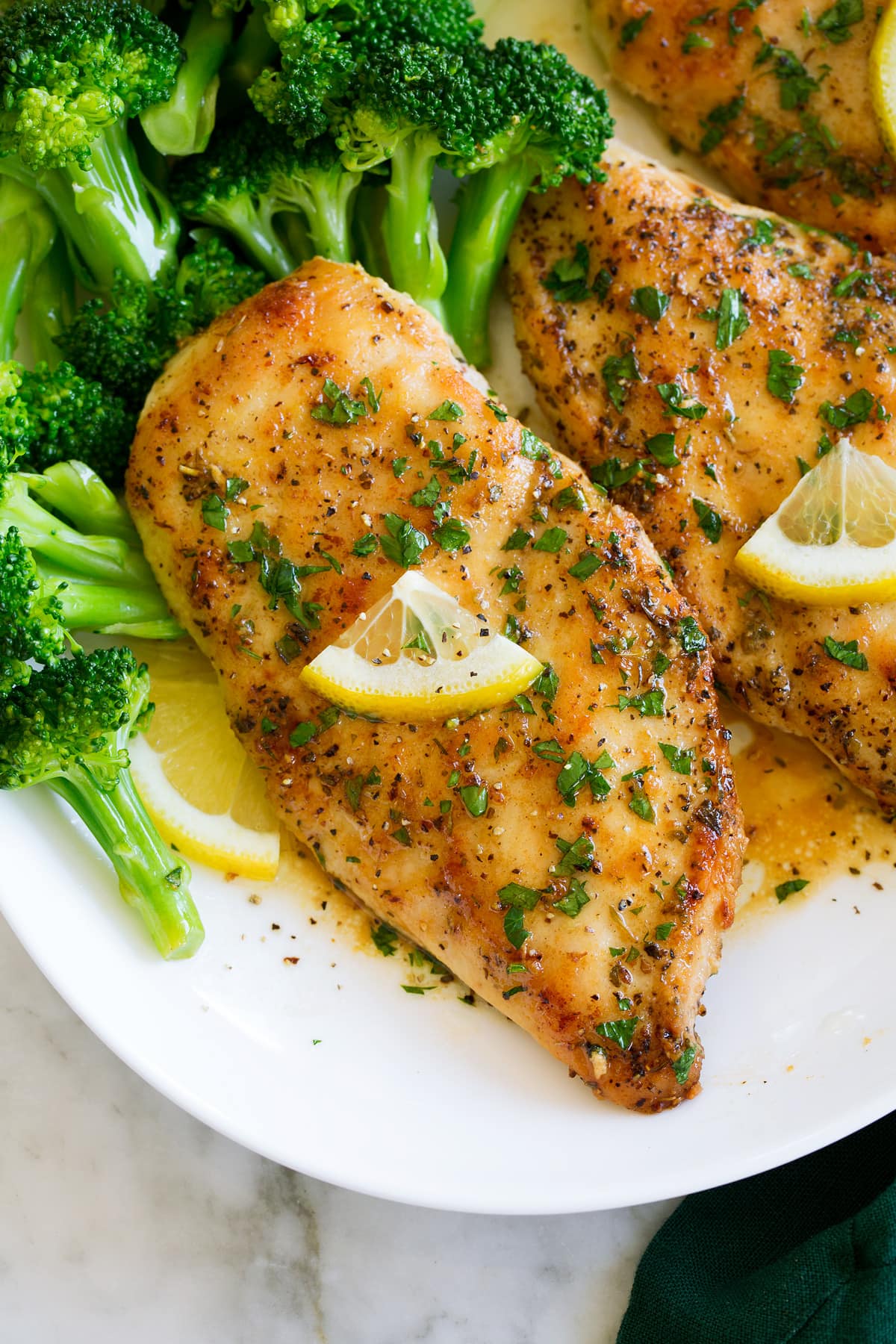 Close up photo of lemon pepper chicken shown from above on a white plate.
