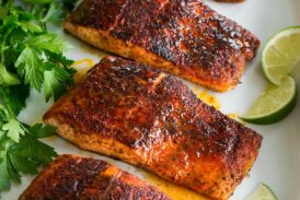 Photo: Blackened salmon shown topped with buttery honey lime sauce. Parsley and limes are shown as garnishes.