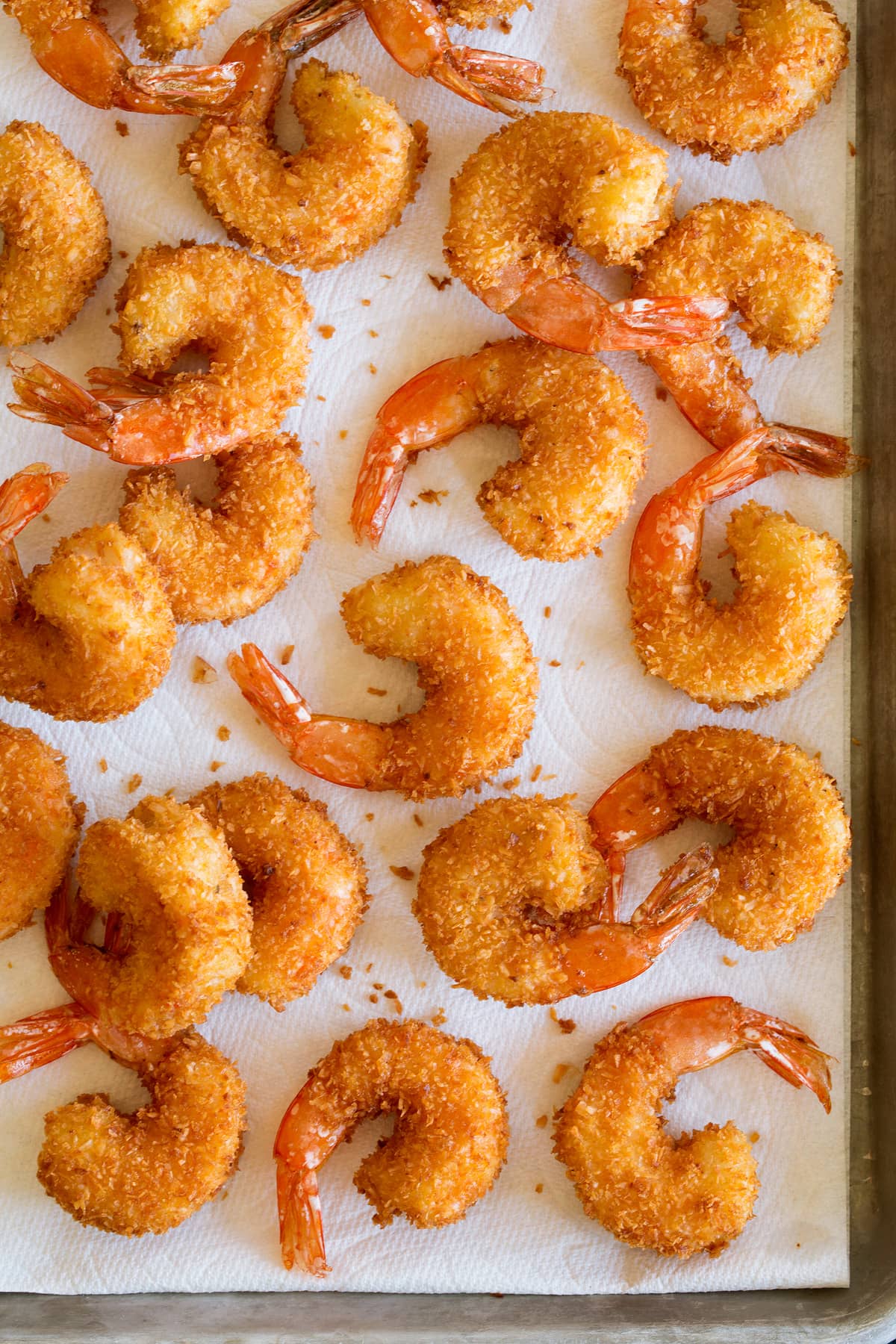 Overhead photo of coconut shrimp shown spread out and draining on paper towels.