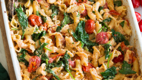 Photo: Baked feta pasta in a white rectangular baking dish shown from a side angle.