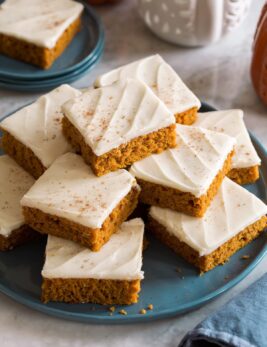 Homemade pumpkin bars stacked on a blue plate.