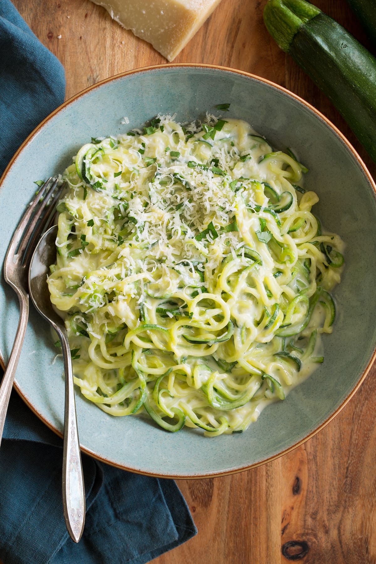 Zoodles tossed with alfredo sauce, shown served in a blue pasta bowl.