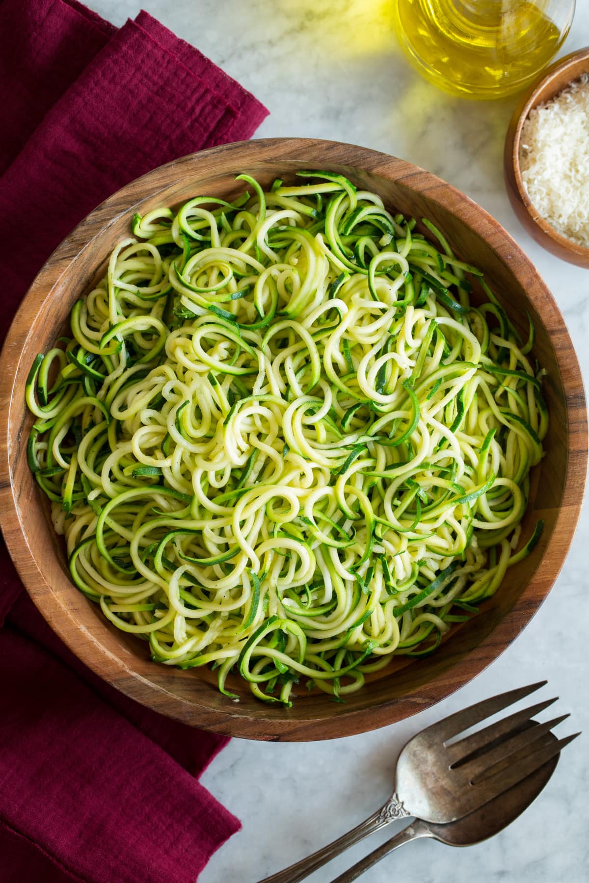 Plain cooked zucchini noodles shown in a wooden bowl on a white marble surface.
