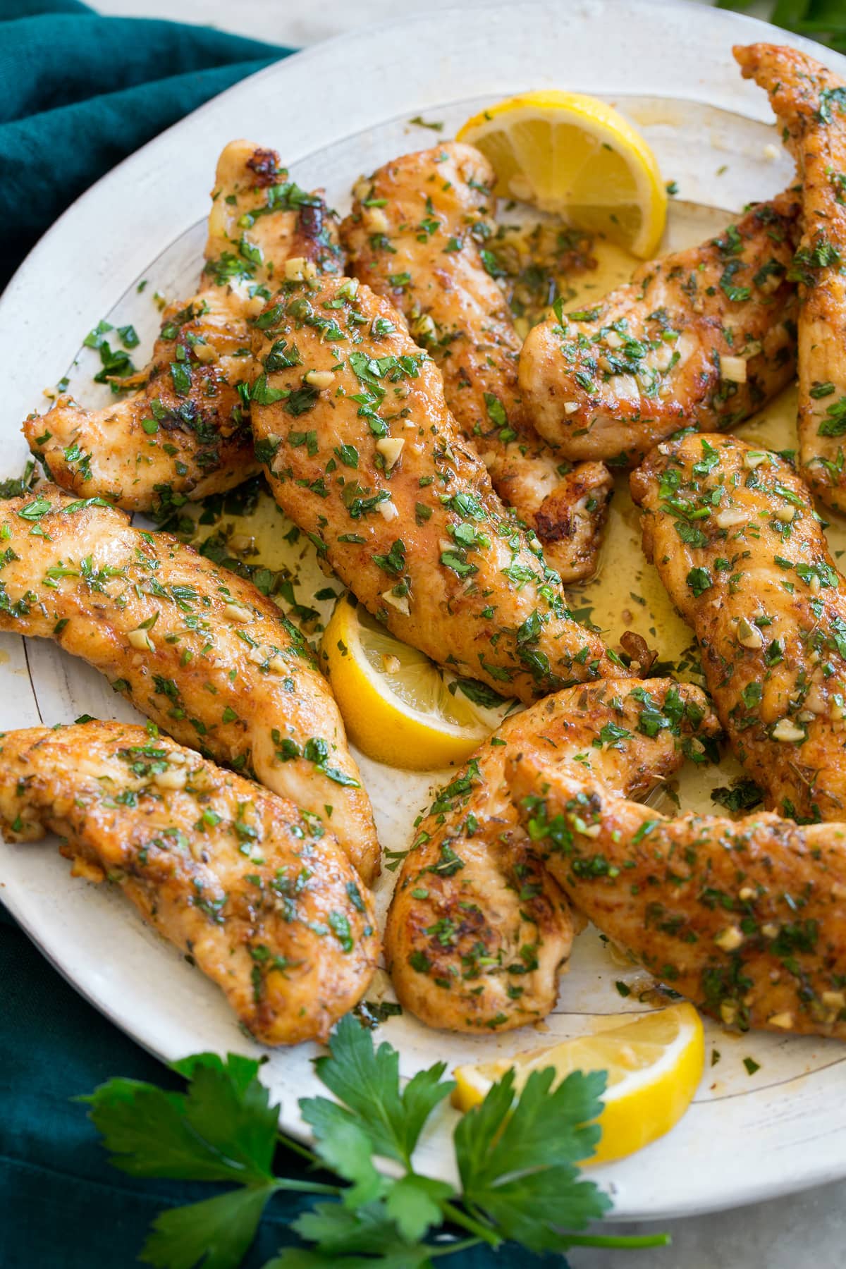 Seared chicken tenders with butter and lemon shown close up.