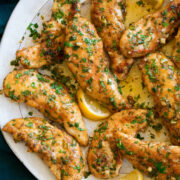 Chicken tenders with a garlic lemon and butter sauce shown on a serving plate.