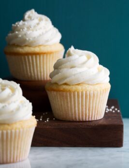Photo of three vanilla cupcakes with vanilla buttercream frosting.