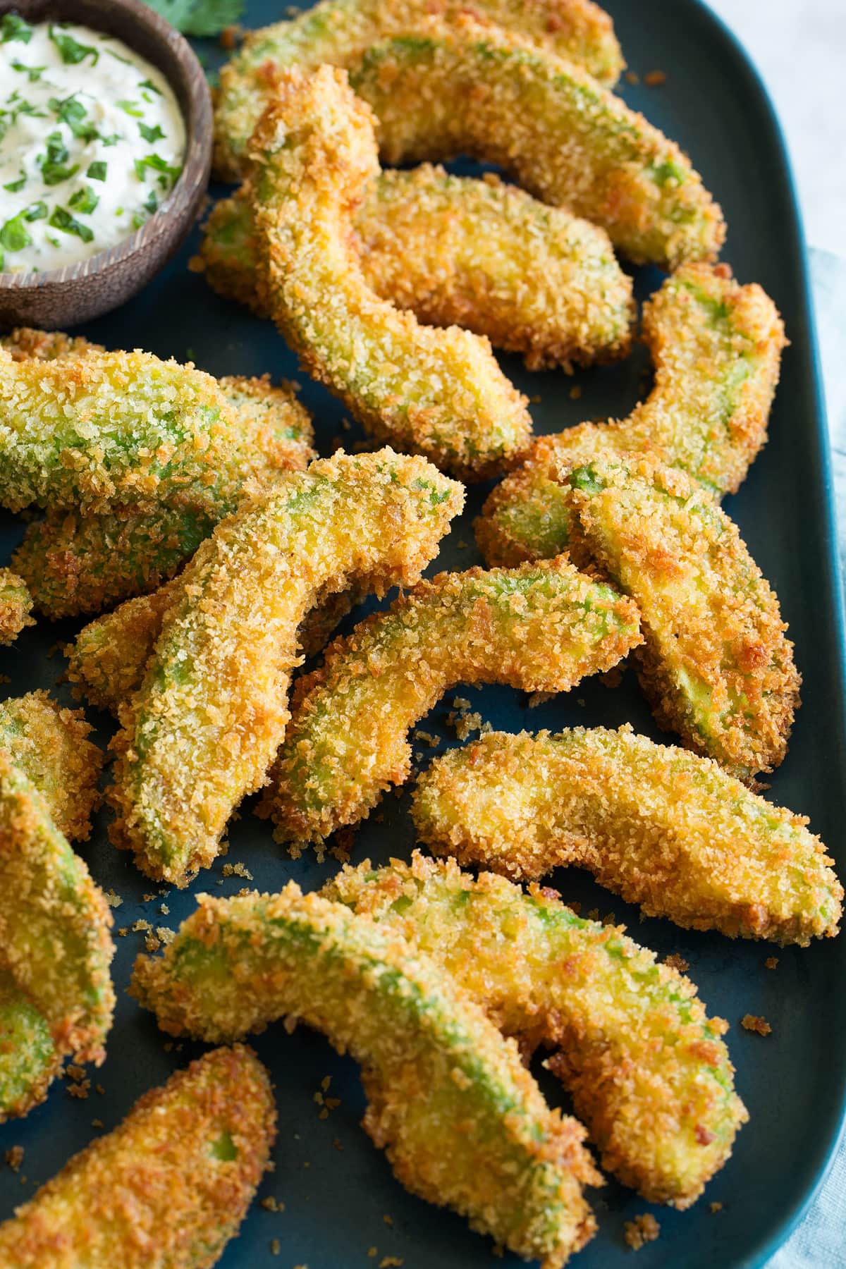 Avocado fries shown piled on a platter from a side angle.