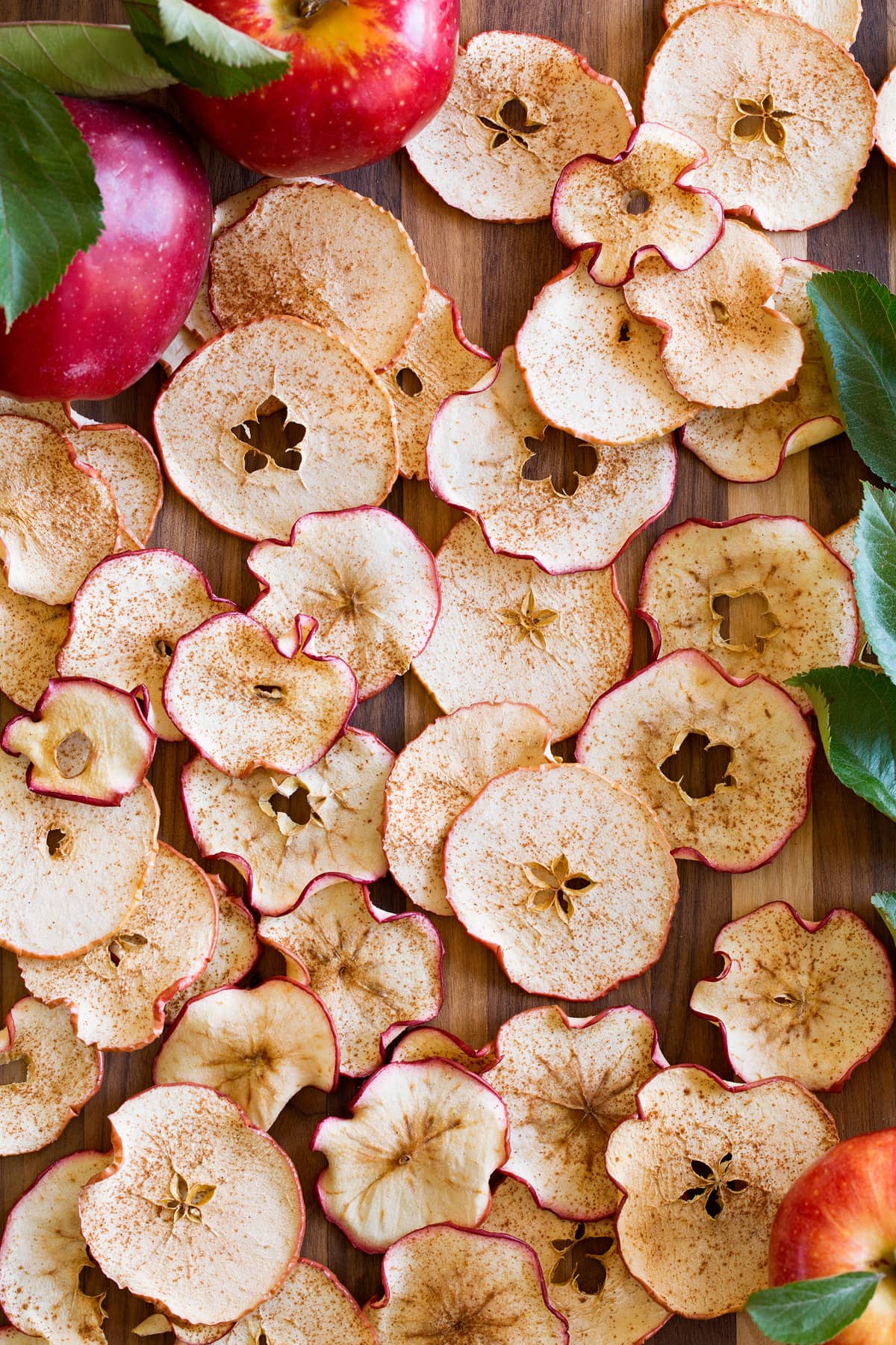 Apple chips spread out on a wooden surface.